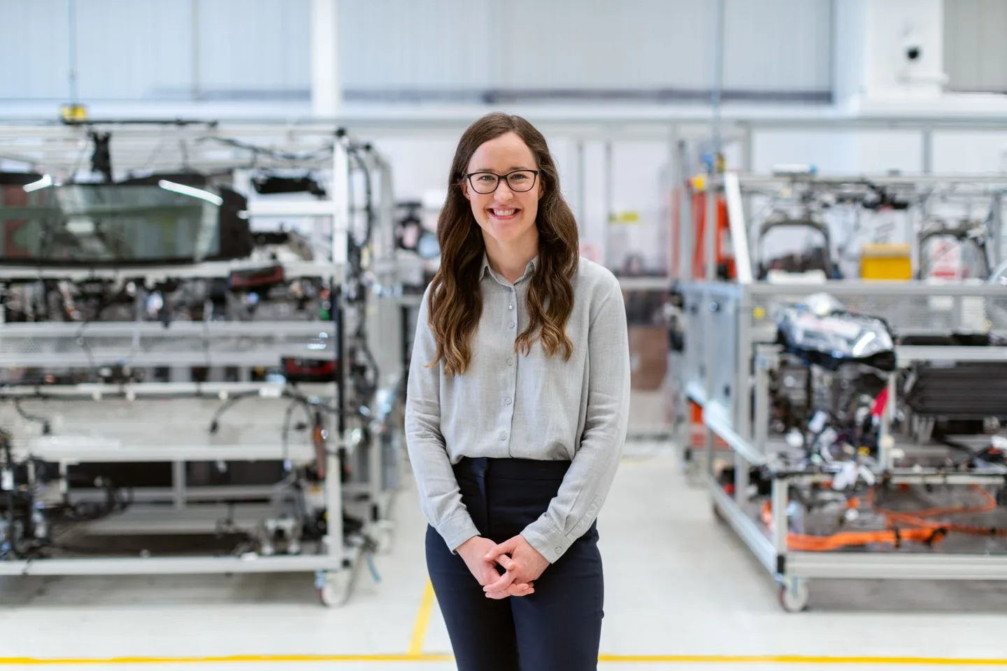 Lächelnde Ingenieurin in einer technischen Werkhalle.