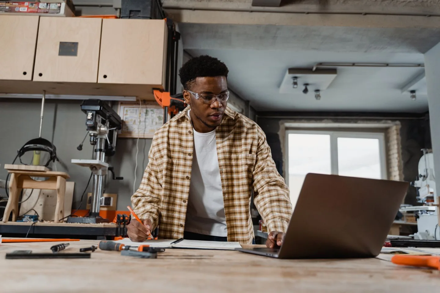 Handwerker plant an einem Laptop an seiner Werkbank.